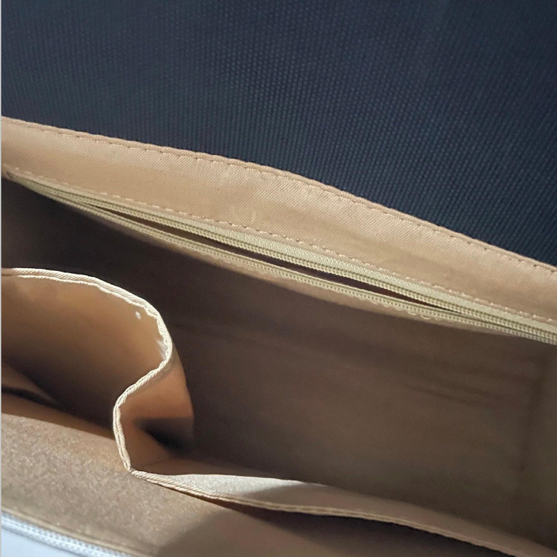 the interior of a tan-colored purse or bag, with a zipper and a flap visible.
