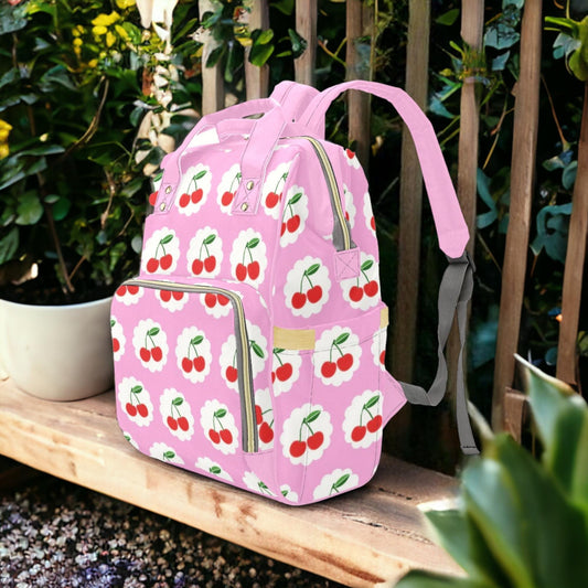 a pink backpack with cherries on it sitting on a bench