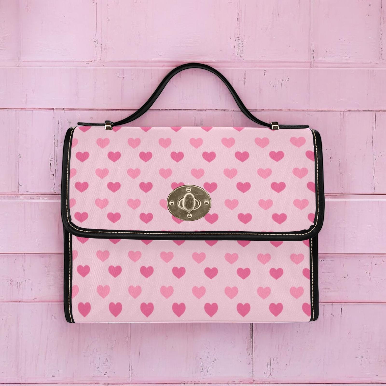 a pink and black purse with hearts on it