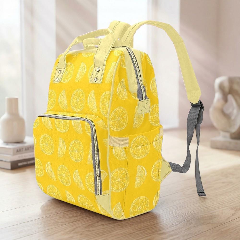 A yellow backpack with a lemon pattern printed on it, sitting on a wooden surface.